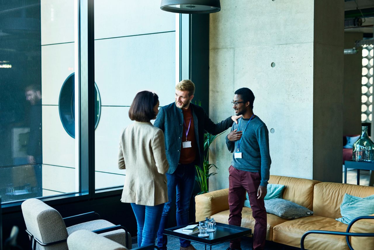 two men and a woman in business casual clothes chatting in a modern office